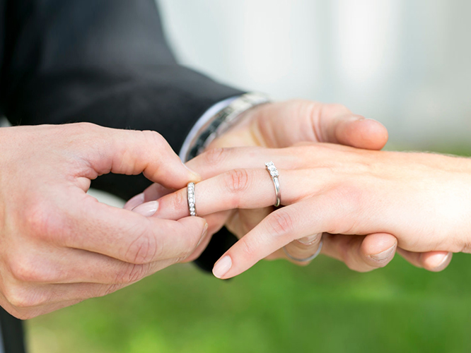 Man puts wedding ring on woman’s hand.