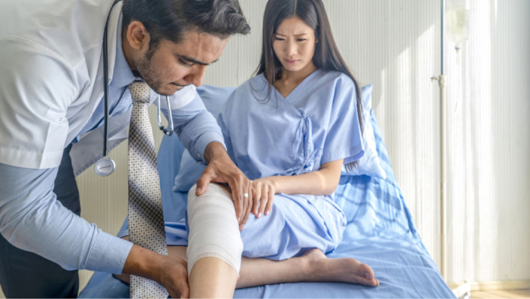 Doctor examines patient’s bandaged leg.