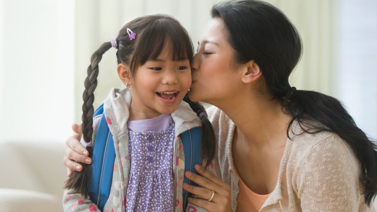Mother kisses daughter on the cheek.