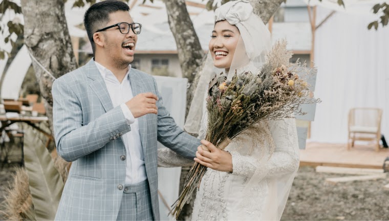 Newlywed couple smiling with wedding bouquet.