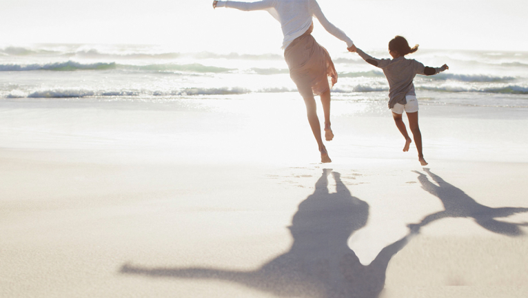 Parent and child running on beach